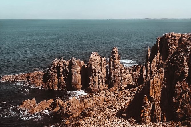 Weathered rock stacks standing off a headland above the surf
